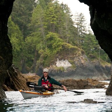 owner and kayak guide Dave Pinel paddling through a rugged sea arch